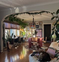 a living room filled with furniture and lots of plants on top of the floor next to a dining table