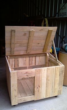 a large wooden box sitting on top of a cement floor next to a metal container