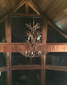 a chandelier hanging from the ceiling in a room with wood paneled walls