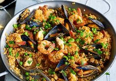 a pan filled with seafood and rice on top of a table