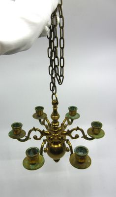 an antique brass chandelier with green glass cups and chains hanging from it's center