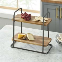 two tiered serving trays with cheese, crackers and grapes on the table