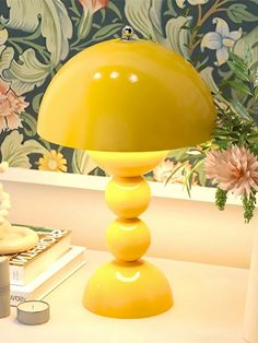 a yellow lamp sitting on top of a table next to a vase with flowers in it