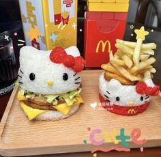 two hello kitty burgers with french fries and ketchup on the side sitting on a wooden tray