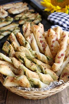 bread sticks with pesto and cheese on them in a basket next to sunflowers