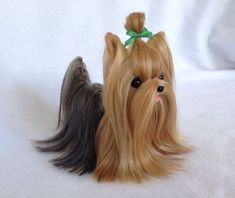 a small dog with long hair and a green bow on its head is laying down