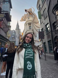 a woman standing in the middle of a street wearing a scarf with an image of a dragon on it