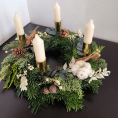 a christmas wreath with candles and greenery