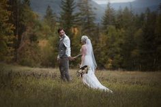 a bride and groom holding hands in a field