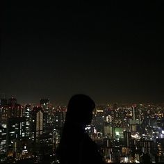 a person standing on top of a tall building at night with city lights in the background