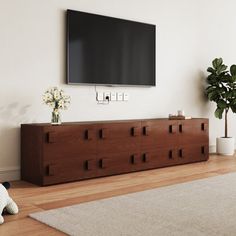 a flat screen tv mounted on the wall above a wooden dresser in a living room