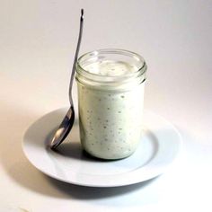 a spoon sitting on top of a white plate next to a jar of yogurt