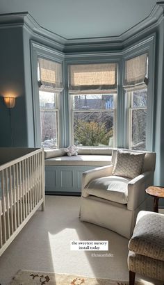 a white chair sitting in front of a window next to a baby's crib