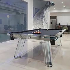 a pool table in the middle of a living room with stairs leading up to it