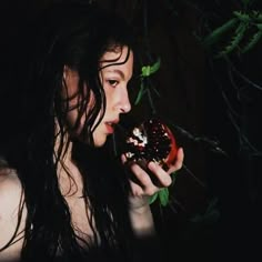 a woman eating a donut in the dark with green leaves on her head and black hair