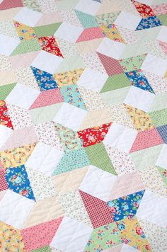 a colorful quilt is laying on top of a tablecloth that has many different colors and shapes