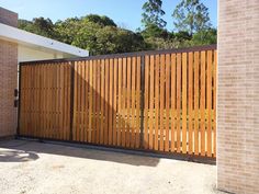 a large wooden gate in front of a brick building with trees on the other side