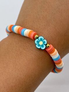 a woman's arm with a colorful bracelet and flower on the end of it