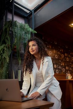 a woman sitting at a table with a laptop in front of her on the desk