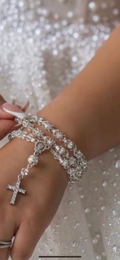 a woman in a wedding dress holding onto a cross bracelet