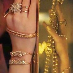 a woman's hand with gold rings and bracelets on her wrist, next to a mirror