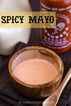 a wooden bowl filled with sauce next to a bottle of mayo