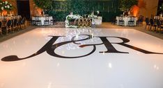 a large dance floor is decorated with white and black flowers, candles, and monogrammed letters