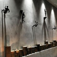 several sculptures are displayed on the wall in an art gallery, with people climbing up and down them