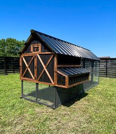 a chicken coop in the middle of a grassy field with a blue sky behind it