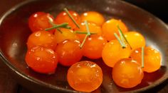 small orange tomatoes in a metal bowl on a table