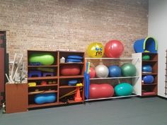 a room filled with lots of different types of exercise balls and gym equipment on shelves