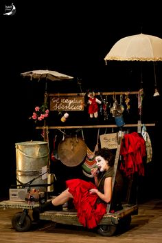 a woman sitting in a chair with an umbrella over her head and other items around her