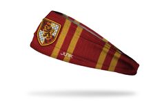 a red and yellow striped headband with a crest on the side, in front of a white background