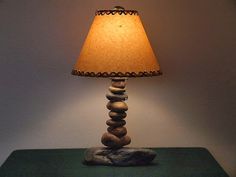 a lamp sitting on top of a green table next to a stone block and paper shade