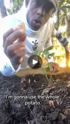 a man is holding something in his hand and looking at the ground with plants growing out of it