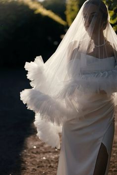 a woman in a white wedding dress with a veil on her head and one arm