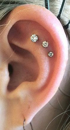 a close up of a person's ear with three piercings