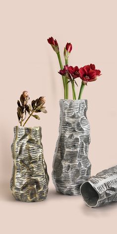 two vases with flowers in them sitting next to each other on a pink background