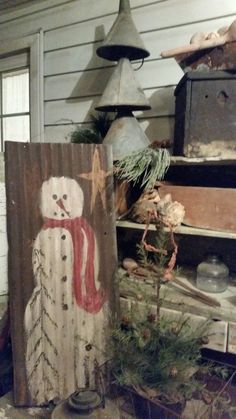 an old wooden sign with a snowman painted on it sitting in front of a house