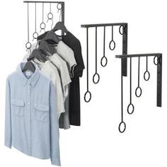 three racks with shirts hanging on them next to a coat rack and clothes hanger