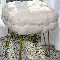 a white sheepskin stool sitting on top of a black and white carpeted floor