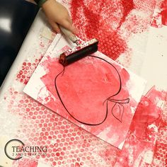 a child's hand with a paintbrush on top of a piece of paper