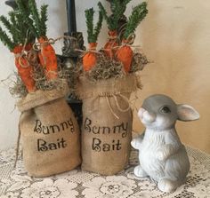 two bags with carrots in them sitting on a table next to a bunny statue