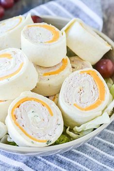 a bowl filled with rolls and grapes on top of a table