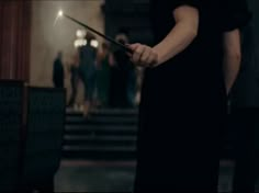 a woman holding a wand in her hand while standing next to some stairs at night