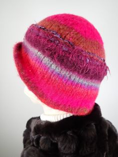 Add some warmth and whimsy to your fall and winter wardrobe with this fun hand knitted boiled and felted 100 percent wool warm winter cloche. This cute wool hat will keep you warm! Dress it up with an oversize shawl or throw it on with a jean jacket. Colors include fuchsia pink, rust and blue with other colorful fun fibers that pop out of the felt for added texture. Embellished with two handmade silk rosettes topped with iridescent vintage glass buttons. Rolled asymmetrical brim for additional i Winter Hand Knitted Cloche Hat, Winter Mini Hats With Short Brim Made Of Yarn, Winter Yarn Mini Hat With Short Brim, Hand Knitted Mini Hats With Curved Brim For Winter, Multicolor Wool Hats, Whimsical Pink Crochet Hat For Winter, Multicolor Winter Cloche Hat With Short Brim, Multicolor Winter Cloche Hat With Curved Brim, Winter Yarn Brimmed Cloche Hat