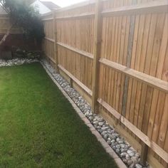 a backyard with grass, rocks and wooden fence