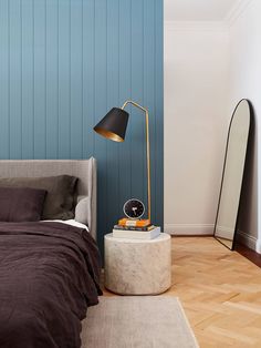 a bedroom with a bed, mirror and lamp on the side table in front of it