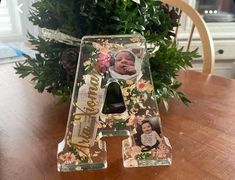 a wooden table topped with a letter shaped photo frame next to a potted plant