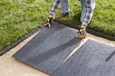 a pair of feet stepping on a mat in the grass